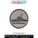 A round INS Baratang patch featuring a detailed grey patrol vessel with antennas deck structure hull contours and shading placed on a textured light grey fabric background with bold navy text INS BARATANG at the lower curve and a reinforced black merrow b